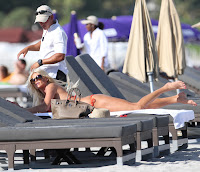 Victoria Silvstedt in an orange bikini laying on the sun bed 
