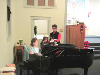 Laurel sings with ten-year-old Taengkwa as ten-year-old Jessie plays the piano.