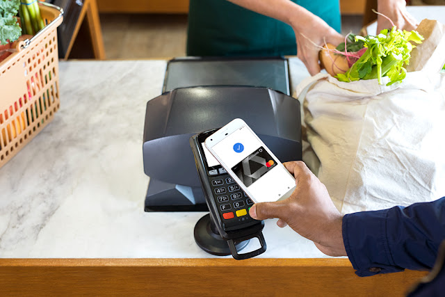 Ein Smartphone wird an ein Kartenlesegerät zum Bezahlen gehalten