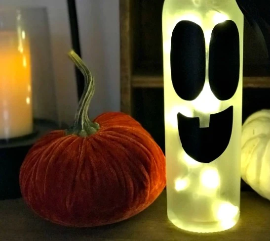 Lighted wine bottle with ghost face and velvet pumpkin