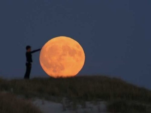 Trick photo shows a person appearing to lay their hand on the Moon
