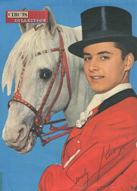 vêtue d'un frac rouge et coiffé d'un haute forme Fredy Knie junior prend la pose avec un cheval blanc