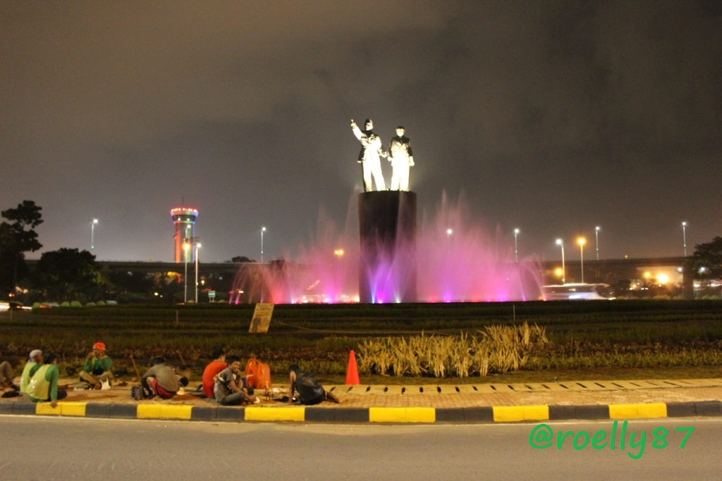 Para pekerja beristirahat di pinggir patung Soekarno-Hatta