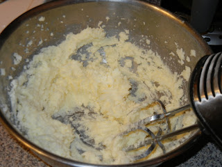 butter and sugar being beat together in a metal bowl with a hand mixer 