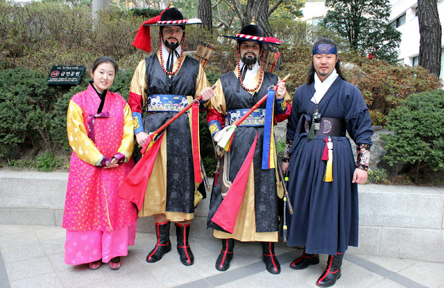 Extranjeros vestidos de guardias tradicionales de palacios coreanos