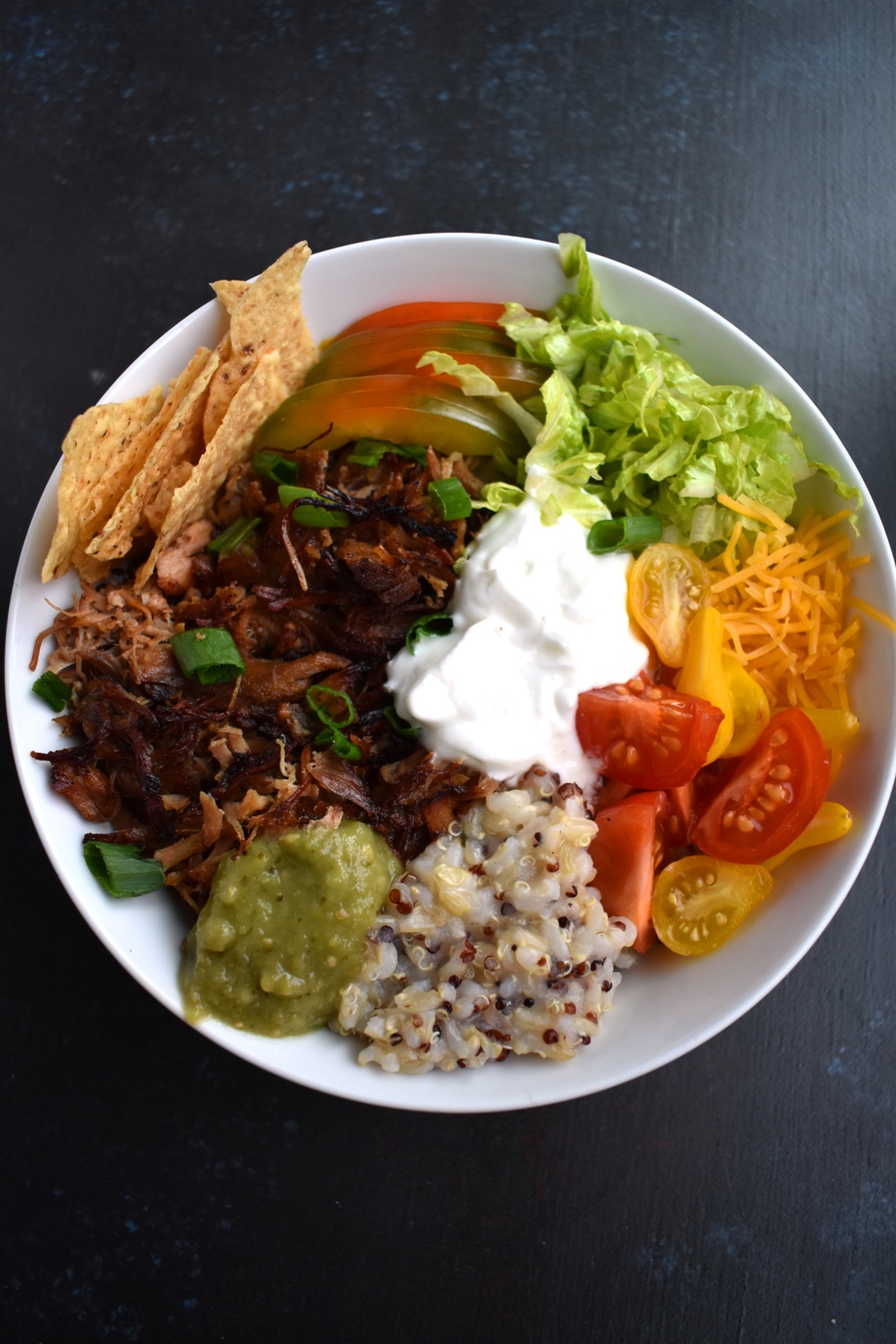 Carnitas Burrito Bowls feature crispy, flavorful pork carnitas, brown rice, cheddar cheese, tomato, green onion, chips, bell peppers and more for a fresh, filling meal ready in about 30 minutes! www.nutritionistreviews.com #mexicanfood #mexican #burrito #pork #dinner #easydinner