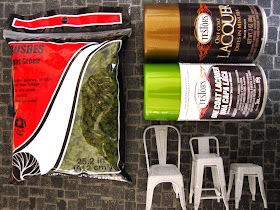 A bag of model railway bushes beside cans of copper and green metallic spray paint and three modern dolls' house miniature 3D printed cafe chairs.