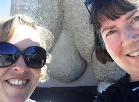 Two women posing in front of the bottom of the Giant Merino in Goulburn.