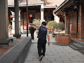 Man wearing "Taipei Baoan Temple" pointing a man in the right direction