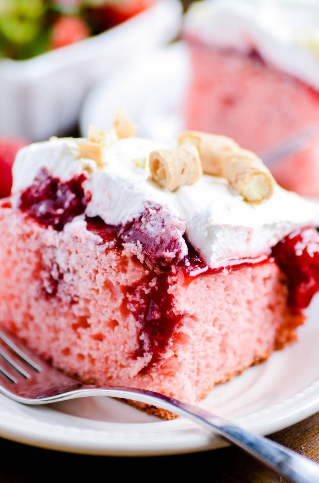 Strawberry Cake soaked in homemade strawberry sauce, spread with a whipped topping, and topped with white chocolate-filled pirouettes. 