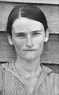A black and white photograph of a woman looking directly into the camera.