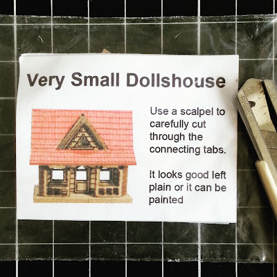 'Very small dollshouse' in its packaging, on a cutting board with a cutting knife next to it.