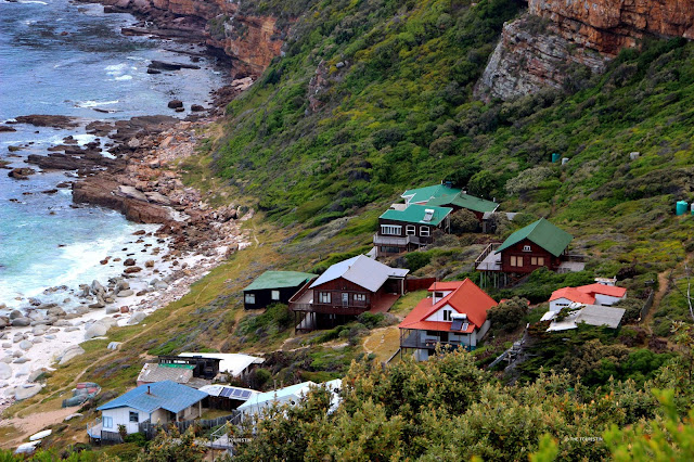 Rooftops of colourful beach houses built on a slope right on the ocean shore.
