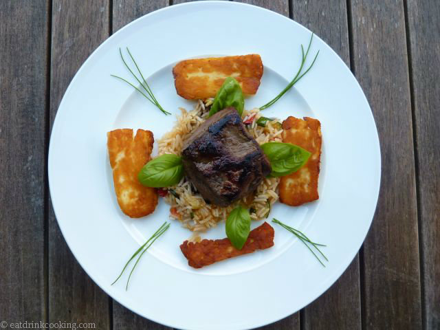 Teller mit Gemüse-Reis, Steak und Halloumi, Basilikumblättern und Schnittlauchstreifen