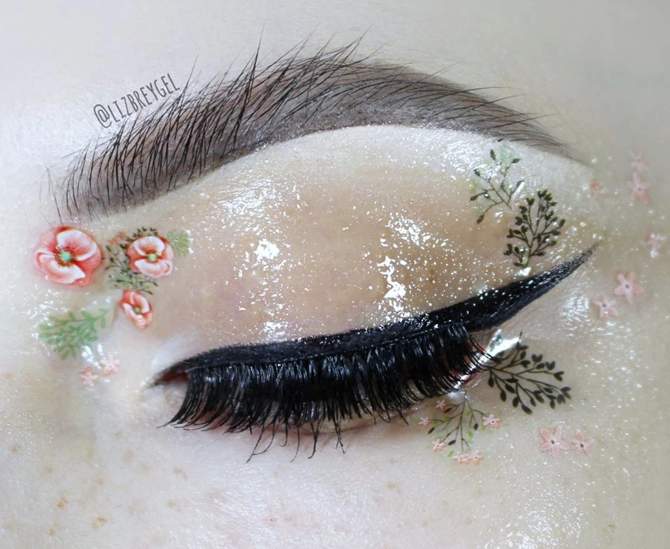 a close-up of an eye with bushy eyebrow makeup look, freckles and stickers