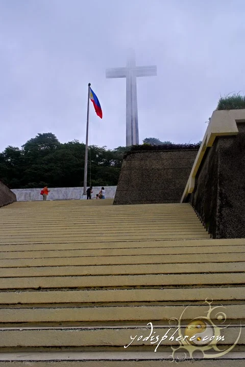 Philippine Flag waving against the towering Cross 