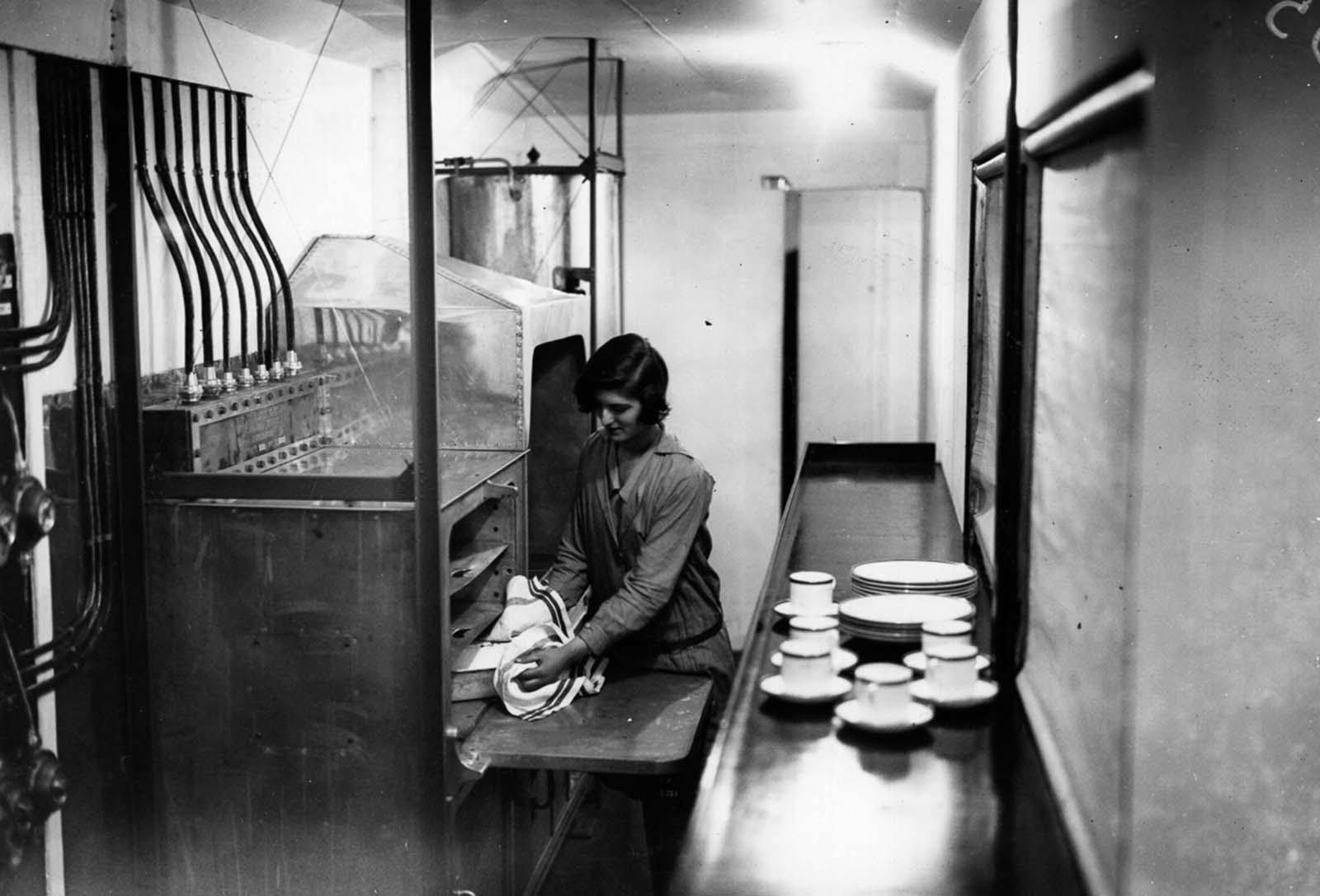 A maid prepares a dish in the airship's galley. 1929.