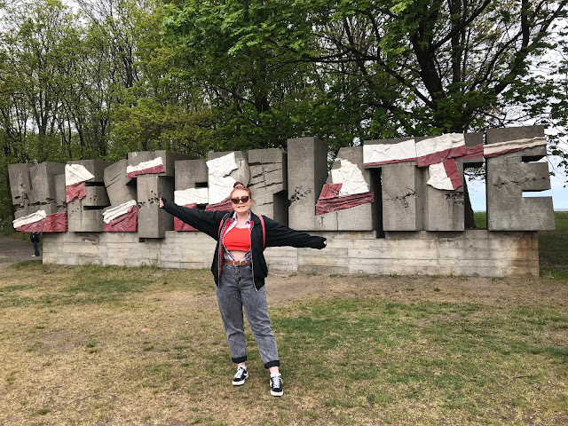 me with arms outstretched in front of a sign saying Westerplatte
