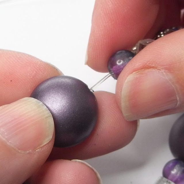 Sliding the knot in the beading elastic inside a large bead to hide it