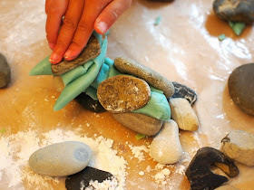 boy building with play dough and rocks