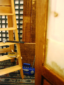 Modern dolls' house miniature cafe under renovation, with tools on a ladder and a radio on the floor.