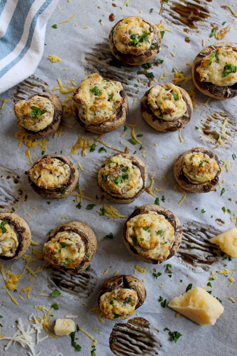 Cream Cheese Stuffed Mushrooms on a parchment-lined baking sheet with a blue and cream striped kitchen towel.