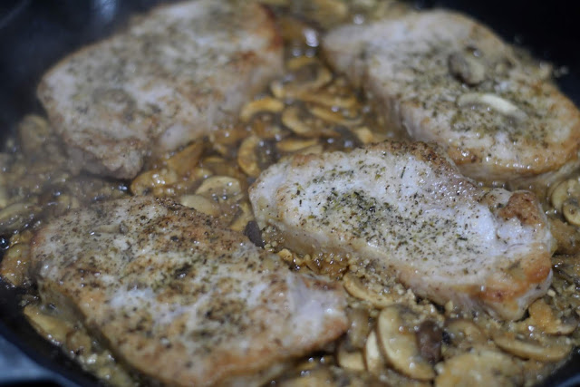 The fully cooked pork chops with the mushrooms in the pan. 