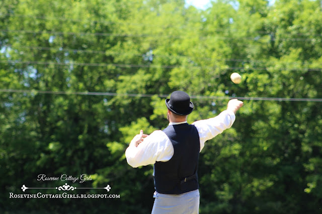 Photo of a man throwing a baseball. He is in a vintage uniform. The article is about Vintage Baseball teams by rosevinecottagegirls.com