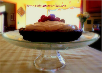 Flourless Chocolate Cake with Mocha Frosting: A thick, dense cake made with dark chocolate, topped with a light mocha frosting and fresh berries | Recipe developed by www.BakingInATornado.com | #recipe #cake #chocolate