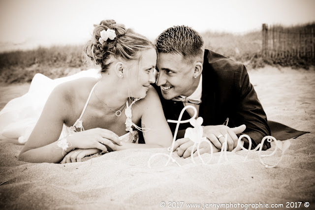 portrait mariés allongés dans le sable en sépia avec love
