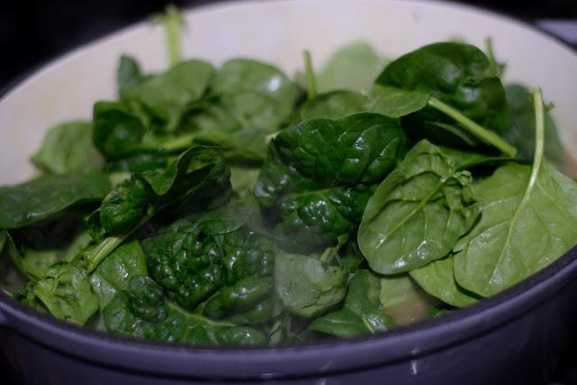 Spinach being added to the soup. 