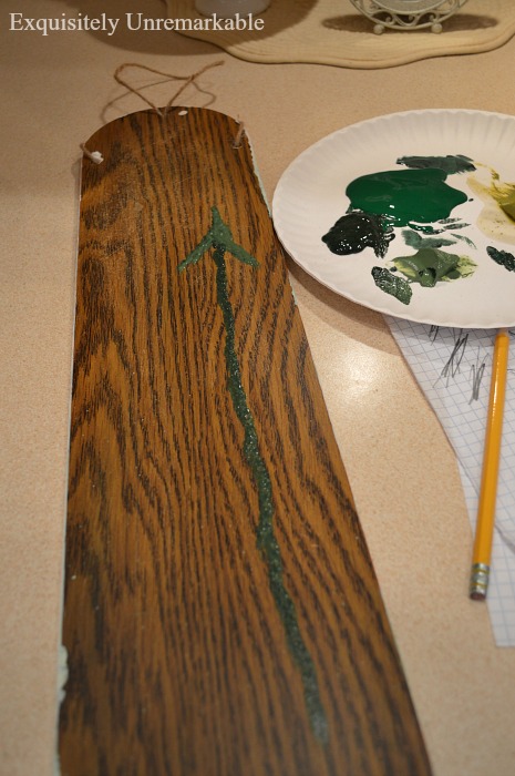 One line of green paint vertically on celling paint and one upside down v crossing it among paint supplies
