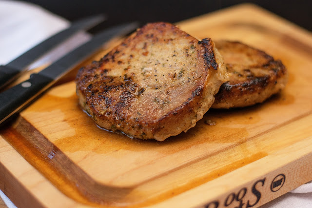 The finished pan seared pork chops on a cutting board. 