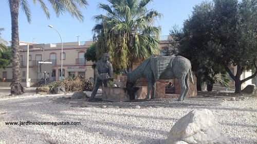 Rotonda faunística en la que un romero da de beber a un burro