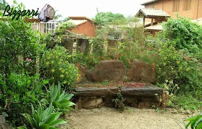 Banco de pedra no jardim, com pedra moledo, com a execução do paisagismo com o piso com pedregulho do rio.