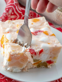 Frozen fruit salad is a blast from the past. This vintage recipe is a cool and delicious way to eat your fruit. It is at home at all of our holiday meals, but would also be a fun summer side dish! fork going into a piece of frozen fruit salad with pears, cheeries and marshmallows showing