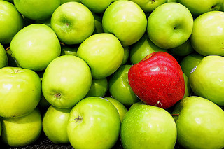 manzana roja rodeada de manzanas verdes