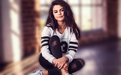 Selena Gomez sentada mirando a cámara con fondo desenfocado