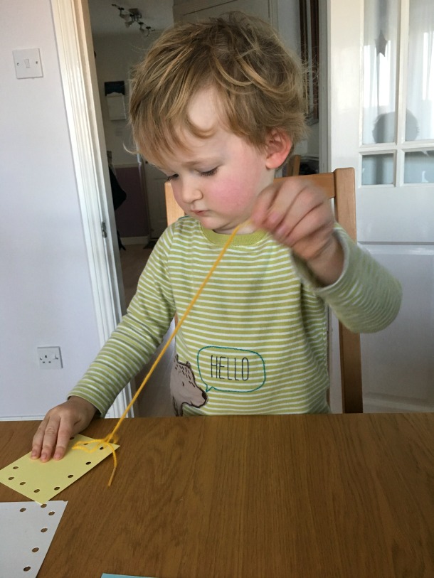 5-minute-games-for-toddlers-lacing-image-of toddler-threading-yarn-through-holes-in-card