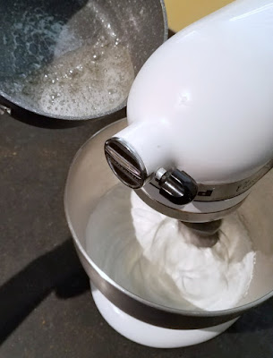 pouring hot sugar syrup into mixer that is beating egg whites