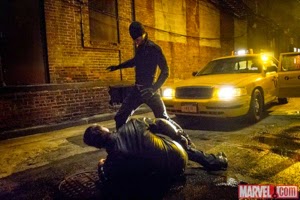 Screen shot of Daredevil in action, at night, with police car nearby, man beaten on the ground at his feet