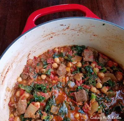 Moroccan Lamb Stew is hearty, flavorful and warm. It is perfect nestled on a bed of couscous and is sure to leave you full and satisfied. pot with stew made from lamb, tomatoes, kale, chickpeas etc.