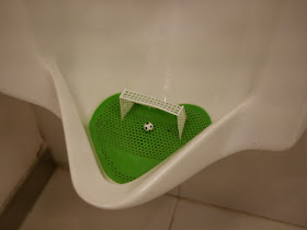 urinal with a miniature football (soccer ball) and net at the bottom