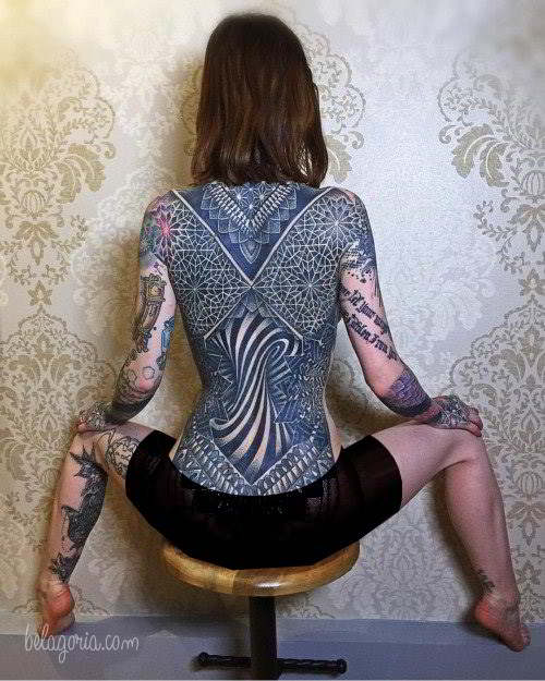 Sensual modelo sentada lleva Tatuaje gigante de geometria sagrada en la espalda