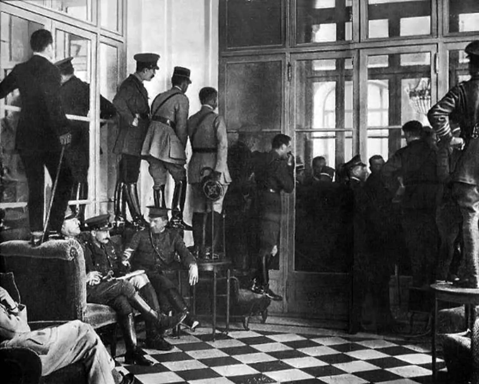 Military officers and politicians climbing over furniture to watch the signing of the Treaty of Versailles in the aftermath of World War 1. June 28th, 1919. 
