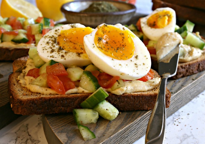 Breakfast toast with hummus, tomatoes, cucumbers and jammy eggs.
