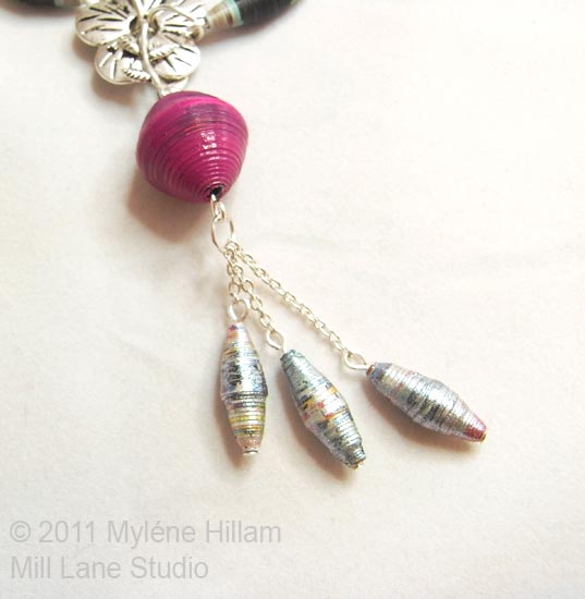 Necklace detail - fuchsia bead and three pearl-coloured dangling paper beads 
