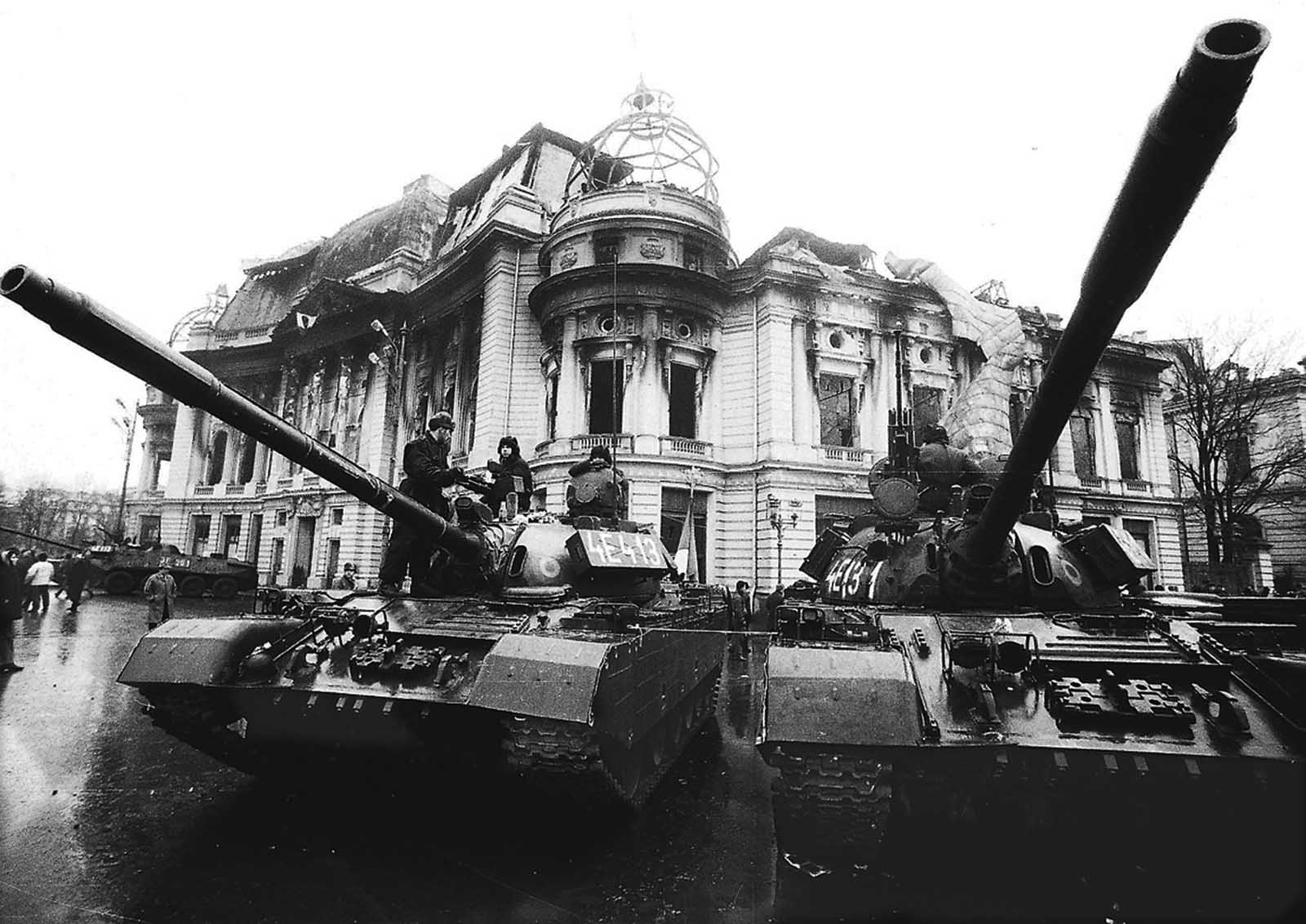 Tanks in front of a burned government building.