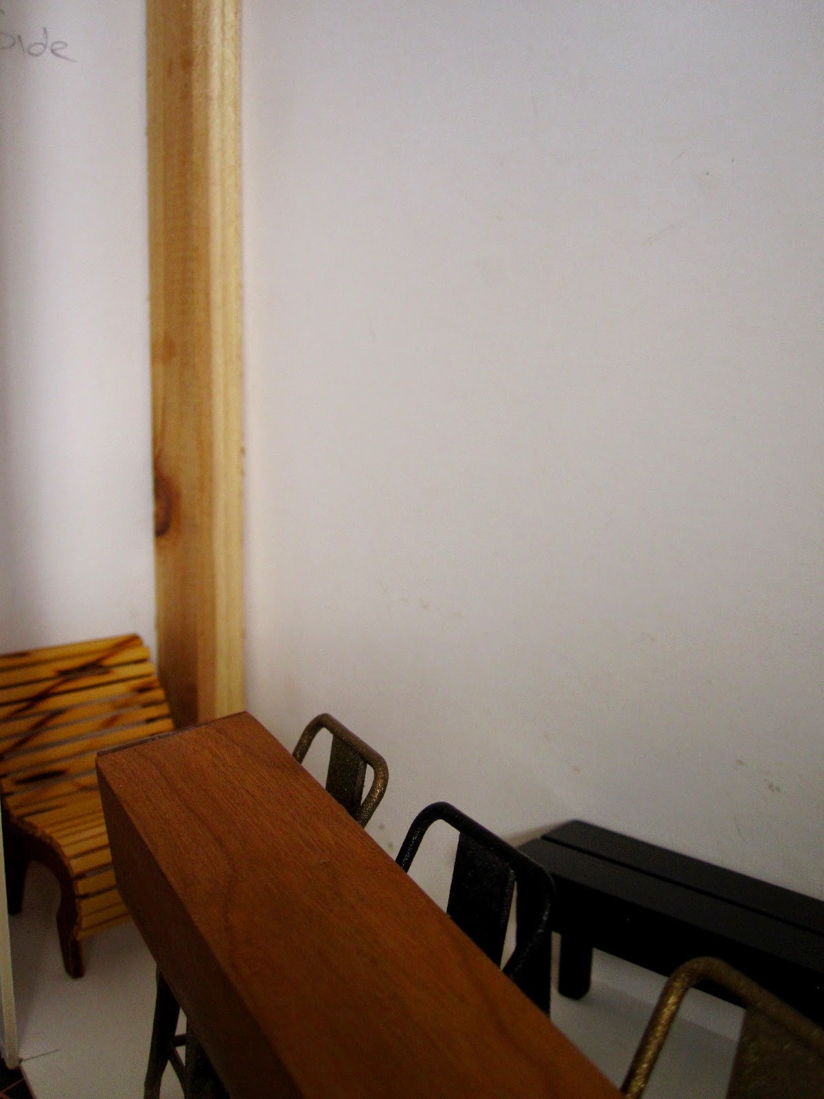 Modern dolls' house miniature cafe, half built with mock up of a window seating and a corner chair set up.