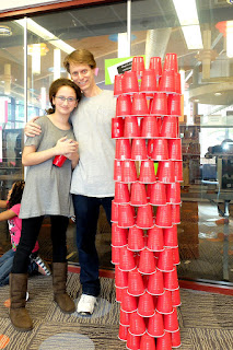 Melanie and dad George conquered the speed round with a cylindrical tower. Melandie and dad George stand proudly beside a cyndrical tower made of red plastic cups.